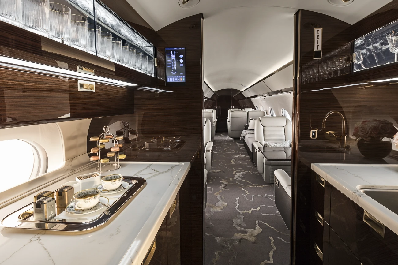 Discover Sunwest Aviation’s G650ER and experience its luxurious interior. The full-service galley and open cabin layout shown here highlight Gulfstream design built for seamless long-range charter flights with maximum comfort.